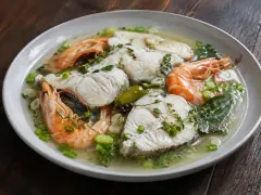 White fish steaks and whole pink prawns in a clear lime and herb court-bouillon scattered with cive.