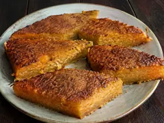Dense caramel-brown wedges of sweet potato and coconut cake showing a moist golden interior on a rustic plate.