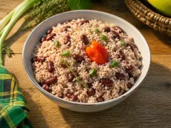 A pot of fluffy pale-pink rice speckled with dark red kidney beans and thyme leaves, with a whole Scotch bonnet pepper resting on top.