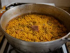 A pot of orange-stained rice studded with whole pigeon peas, diced ham, and green olives.