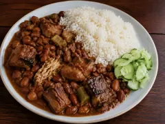Brown beans stewed with smoked pork and salted beef in a thick gravy, served beside white rice and sliced cucumber.