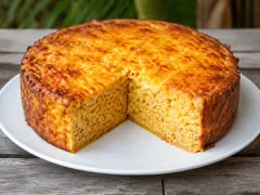 A deep golden baked macaroni pie on a white plate with one wedge removed, showing dense pasta set firm all the way through under a blistered cheese crust.